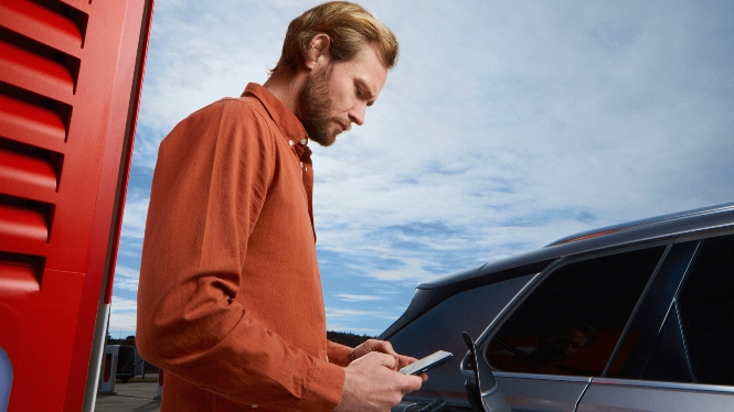 Bilde av mann som ser på mobilen mens han lader