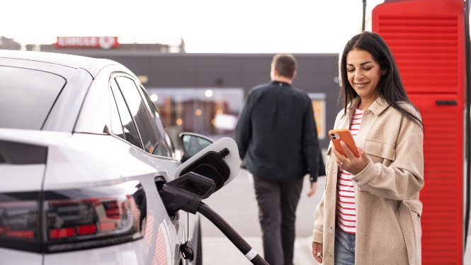 Bilde av dame som ser på mobilen mens hun starter å lade