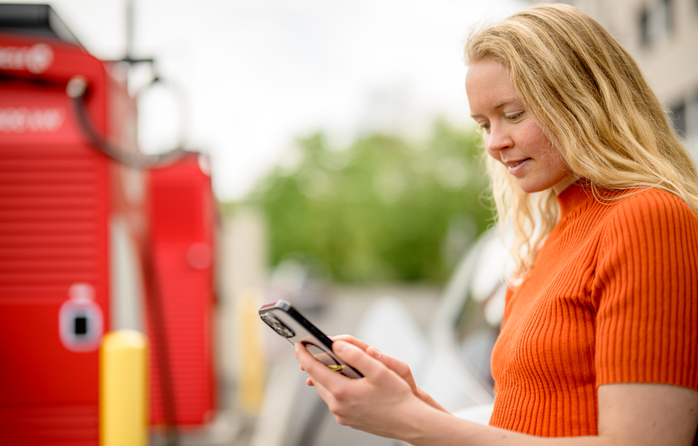 Bilde av dame som ser på mobilen ved laderen