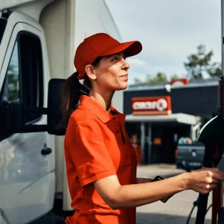 Kvinne foran bensinpumpe