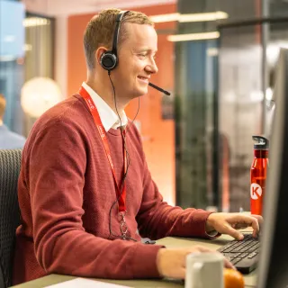 Man helping customers at his desk via headset