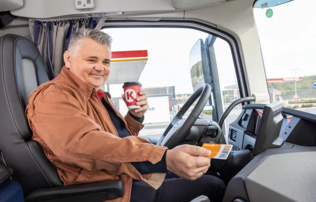 Man in his van showing his Circle K card, drinking a coffee